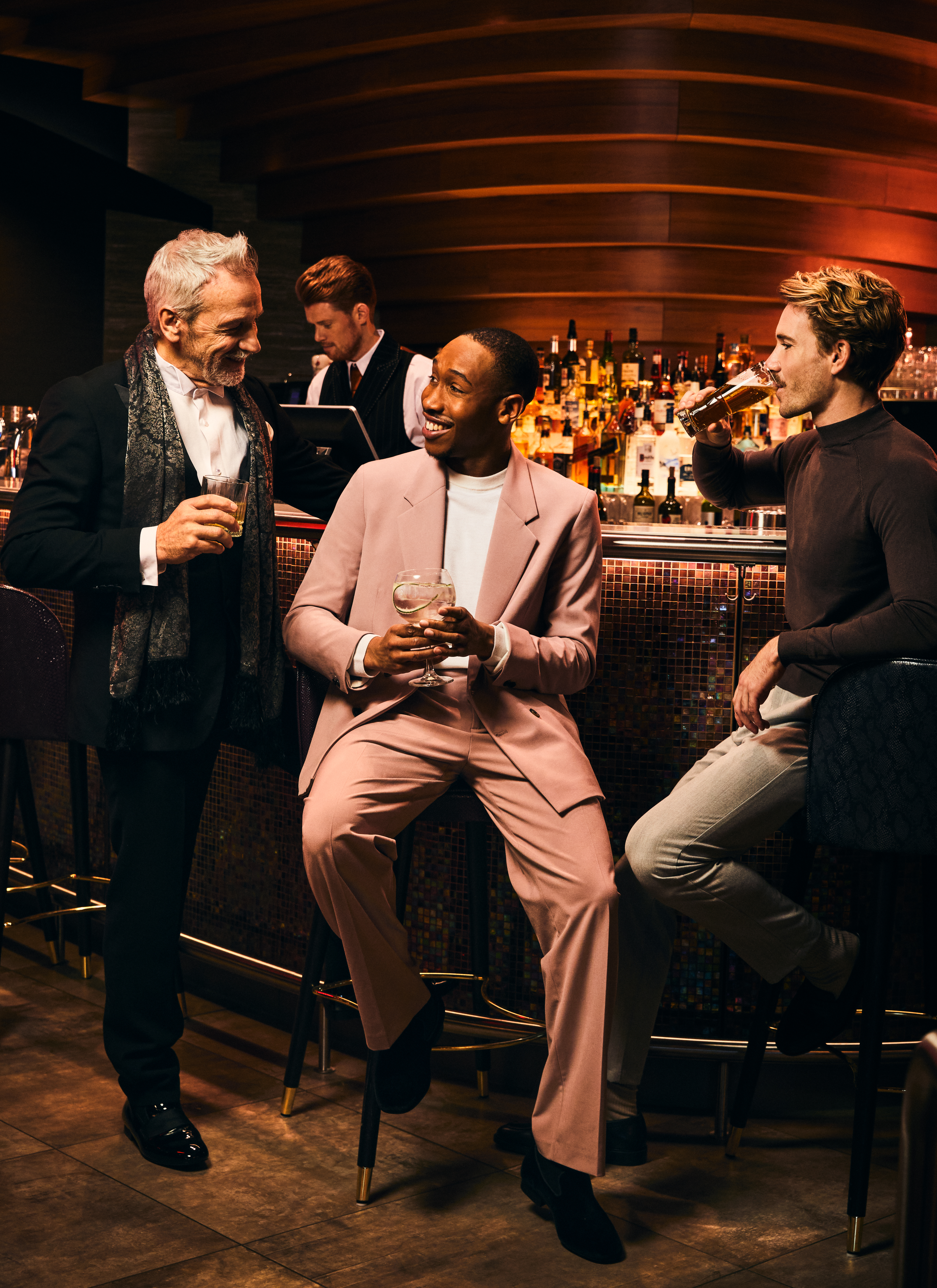 Drie mannen die aan de bar van het casino van een drankje genieten