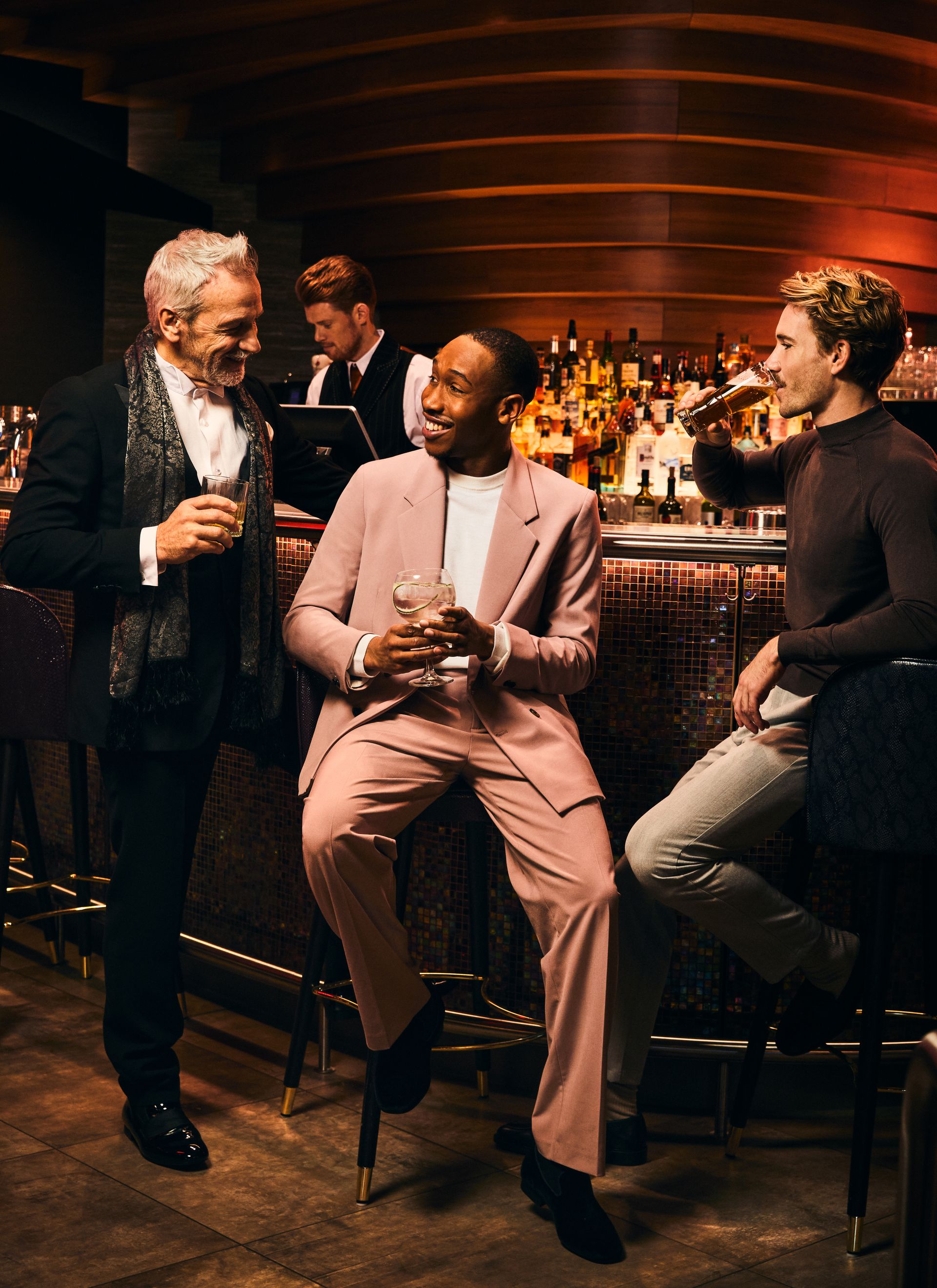 Drie mannen die aan de bar van het casino van een drankje genieten